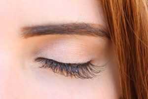 Home Vrouw met lange wimpers die zich afvraagt of wimperserum de investering waard is